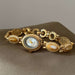 Gold bracelet with a watch face on a brown surface