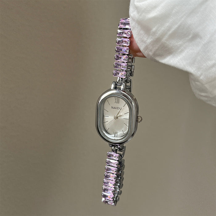 Silver watch with pink gemstone bracelet held by a hand against a neutral background
