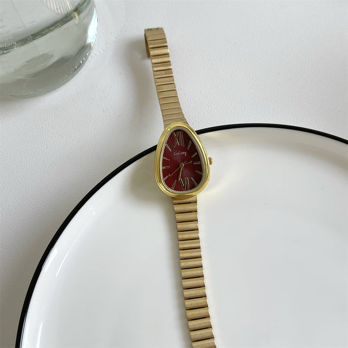 Gold watch with a red face on a white surface