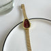 Gold watch with a red face on a white surface
