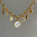Gold charm bracelet with a watch and various charms on a gray background