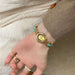 Gold wristwatch with turquoise stones on a wrist against a neutral background