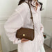 Person holding a brown leather handbag with a white background