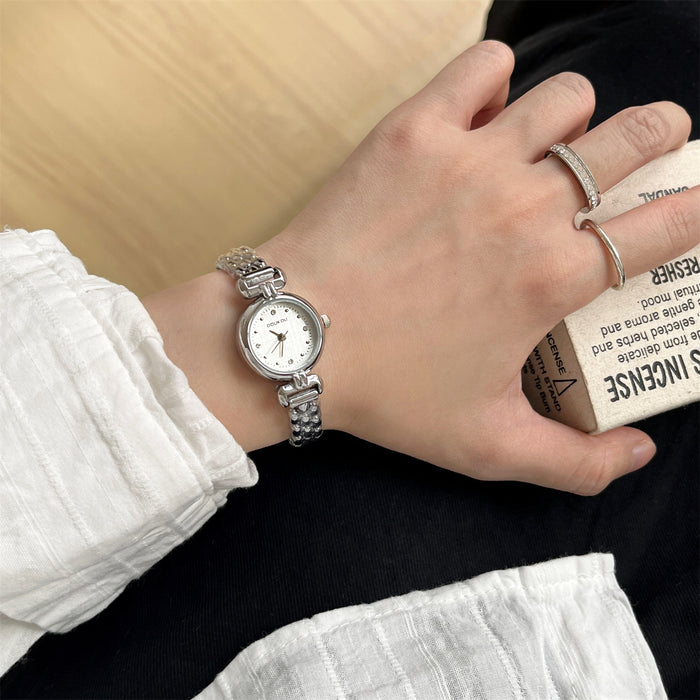 Hand wearing a silver watch with a white face, holding a box of tissues.