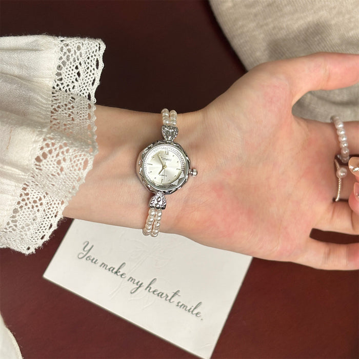 Silver watch on a wrist with a lace sleeve and a card saying 'You make my heart smile' on a brown background