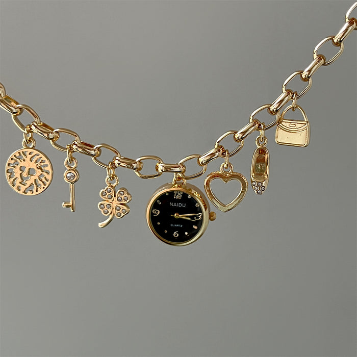 Gold charm bracelet with various charms on a gray background