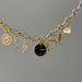 Gold charm bracelet with various charms on a gray background