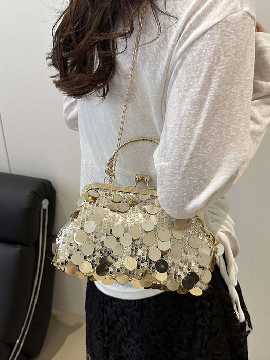 A woman wearing a white long-sleeve top and black skirt carries a small gold-tone handbag decorated with round metallic coin embellishments. The photo is taken from behind, showing the bag over her shoulder in an indoor setting.