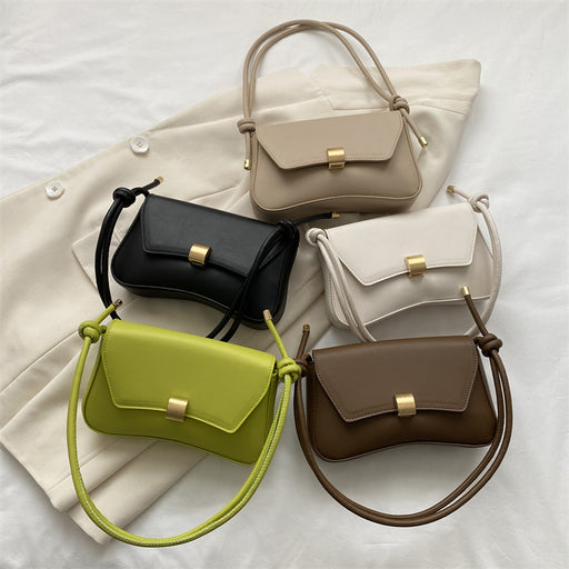 Five handbags in different colors arranged on a light fabric background