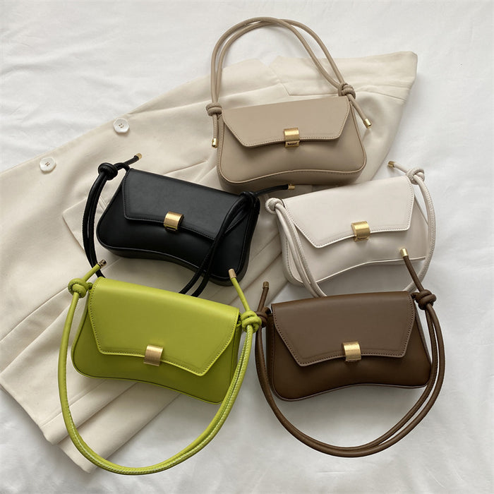 Five handbags in different colors arranged on a light fabric background