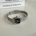 Silver watch with black face on a light background