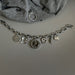 Silver charm bracelet with various charms on a gray surface