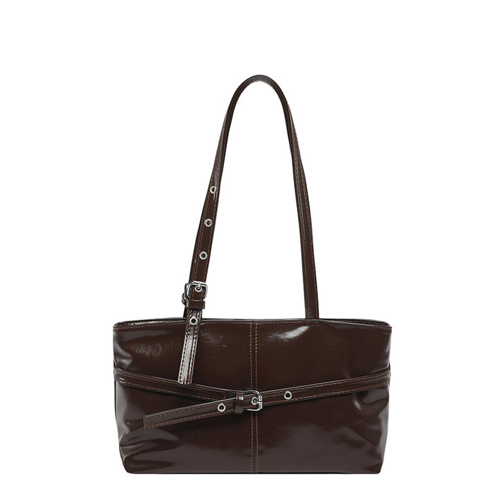 A dark brown patent leather shoulder bag with a wide top opening, a single shoulder strap, and a decorative horizontal strap with silver-tone buckles across the front.