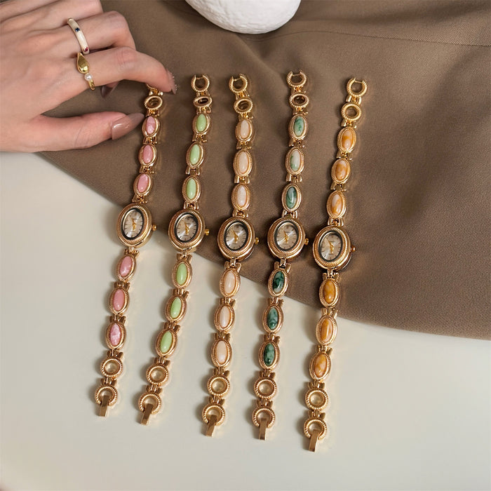 Set of gold bracelets with colorful stones on a neutral background