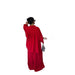 A woman shown from behind wearing a bright red two-piece outfit with a loose long-sleeve top and wide-leg pants, holding a gray handbag against a plain white background.