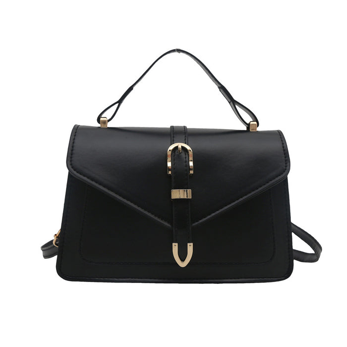 A black faux-leather handbag with a top handle and shoulder strap, featuring a central gold-tone buckle closure on the flap.