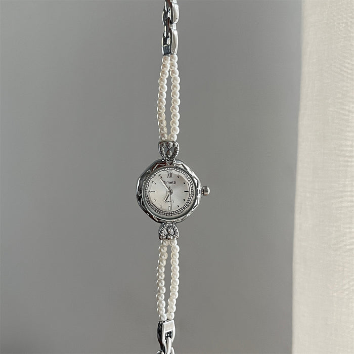 Silver watch with pearl strap on a gray background