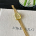 Gold watch on a textured surface with 'MIKE' visible