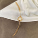 A gold-tone watch with a slim round dial and matching chain bracelet, styled on a white fabric surface over a brown textured background.