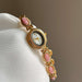 Gold watch with pink gemstones on a white cushion