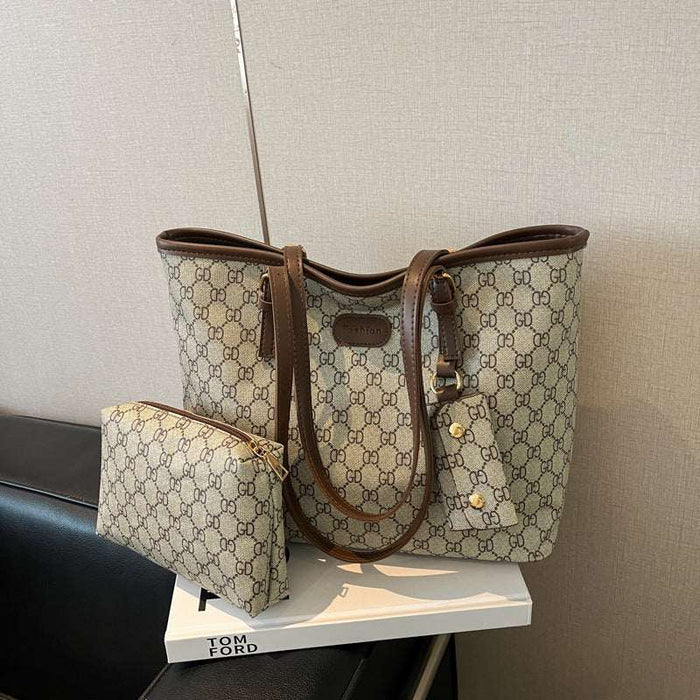 A beige and brown GG Supreme tote bag with matching zip pouch, displayed on a white book on a black leather chair against a textured beige wall.