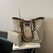 A beige and brown GG Supreme tote bag with matching zip pouch, displayed on a white book on a black leather chair against a textured beige wall.