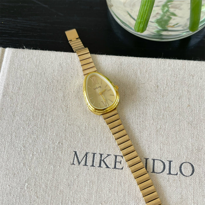 Gold watch on a textured surface with 'MIKE' visible