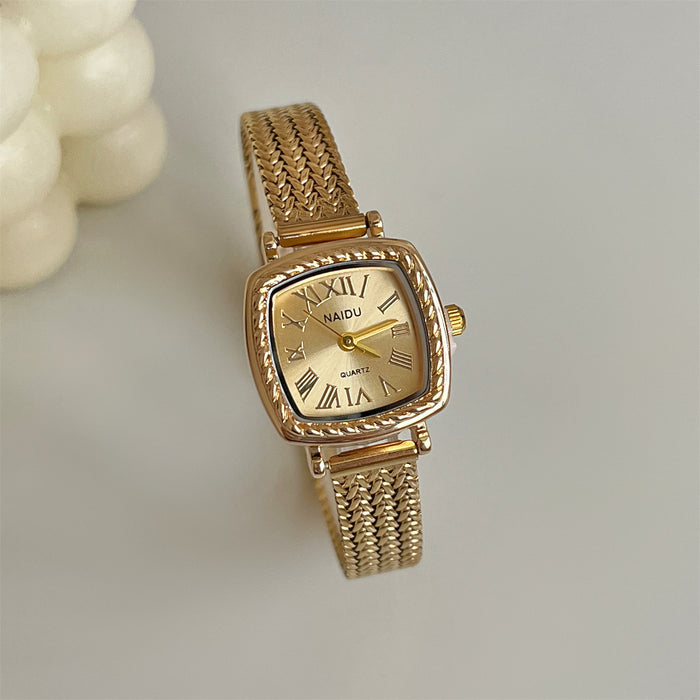Gold watch with Roman numeral design on a light background