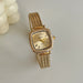 Gold watch with Roman numeral design on a light background