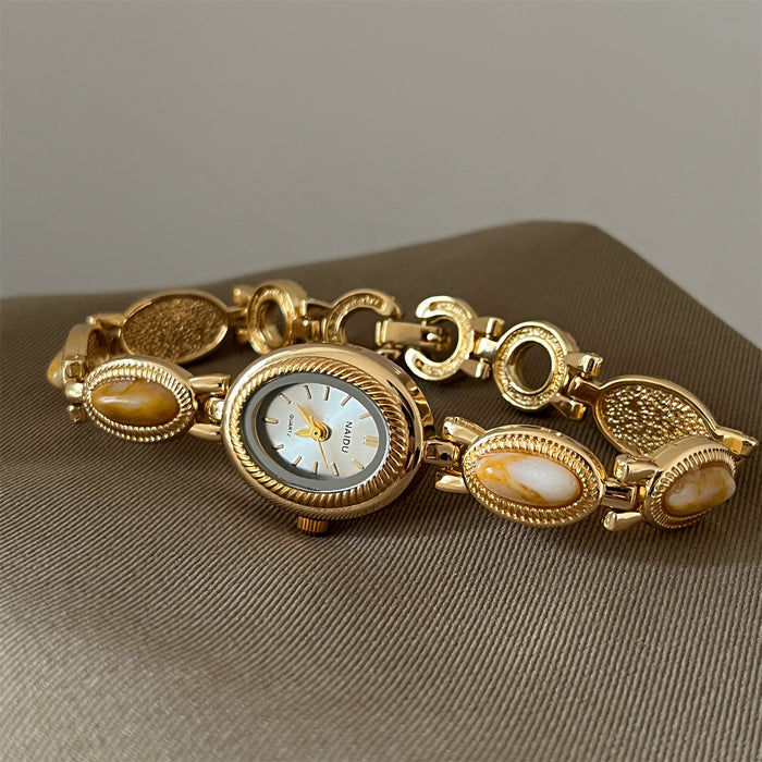 Gold bracelet with a watch face on a brown surface