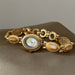 Gold bracelet with a watch face on a brown surface