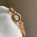 Gold watch with pink gemstones on a white cushion