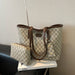 A beige and brown GG Supreme tote bag with matching zip pouch, displayed on a white book on a black leather chair against a textured beige wall.