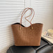 A brown leopard-print tote bag with double shoulder straps and gold-tone hardware, resting on a black leather chair in front of white slatted doors.