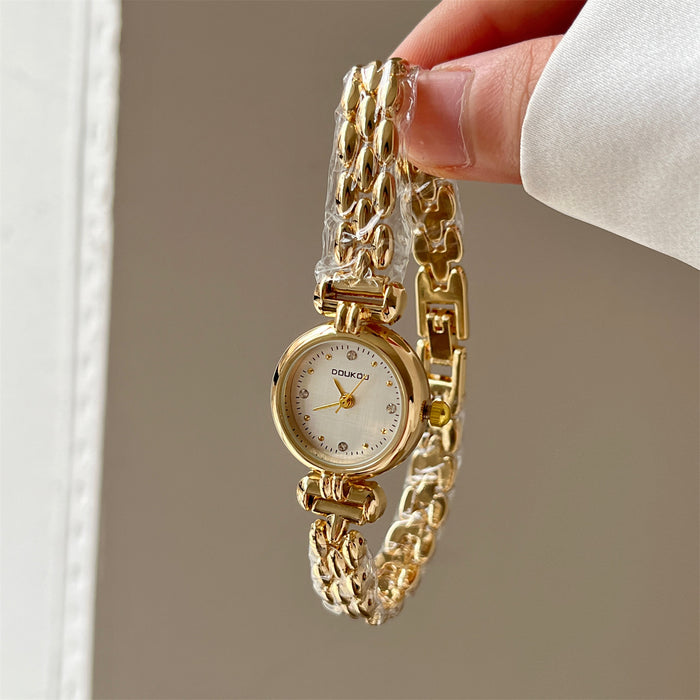 Gold chain watch held by a hand against a neutral background