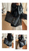 A person wearing a black leather jacket and white pants carries a large dark blue monogram tote bag with brown leather handles and gold-tone hardware in an indoor room. The collage shows multiple views of the same bag being worn.