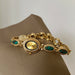 Gold bracelet with gemstone accents on a beige surface