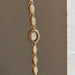 Gold watch with decorative links on a neutral background