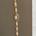 Gold watch with decorative links on a neutral background