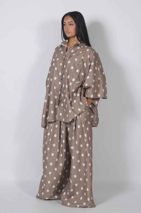 Woman wearing a brown polka dot outfit against a white background