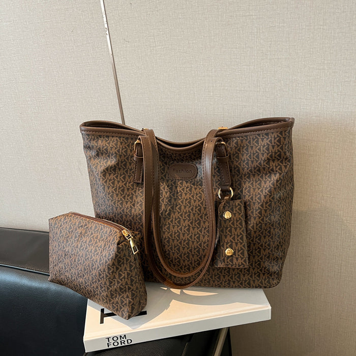 A brown monogram tote bag with matching zip pouch, displayed on a white book against a neutral textured wall.