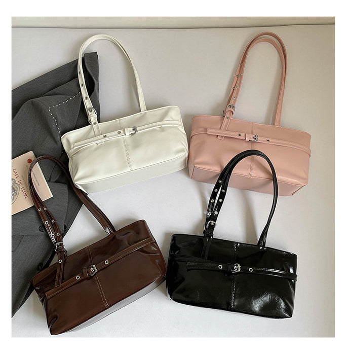 Four structured shoulder handbags arranged on a light neutral background: one cream, one blush pink, one dark brown patent leather, and one black patent leather. A dark gray fabric bag and a small paper tag are partially visible on the left.
