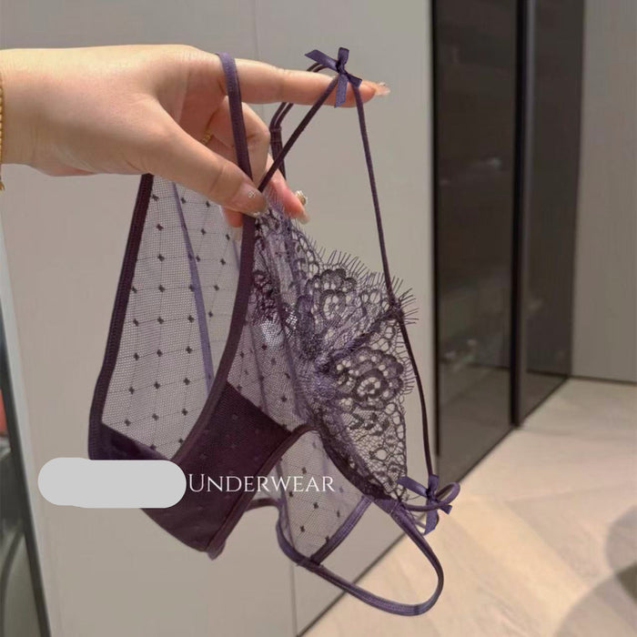 A hand holds up a dark purple lace and mesh panties set with adjustable straps and bow details, set against an indoor background with a visible SANZHIMAO UNDERWEAR watermark.