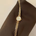 Gold chain watch on a brown fabric background