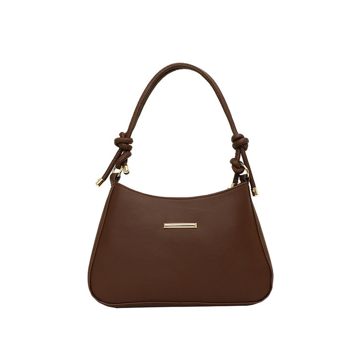 A brown leather shoulder bag with a curved top, knotted handle details, and a small horizontal gold-tone metal accent on the front, shown against a plain white background.