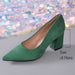 A green suede pointed-toe pump with a block heel, shown on a gray surface with a sparkling multicolor sequin backdrop. A measurement overlay indicates the heel height as 7cm (2.