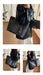 A person wearing a black leather jacket and white pants carries a large dark blue monogram tote bag with brown leather handles and gold-tone hardware in an indoor room. The collage shows multiple views of the same bag being worn.