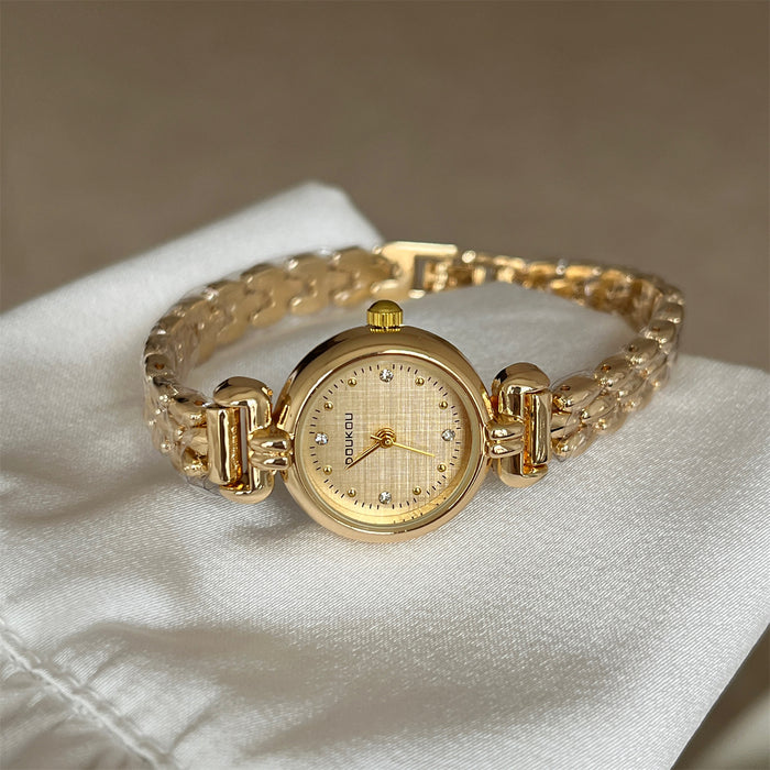Gold wristwatch on a white cushion with a neutral background