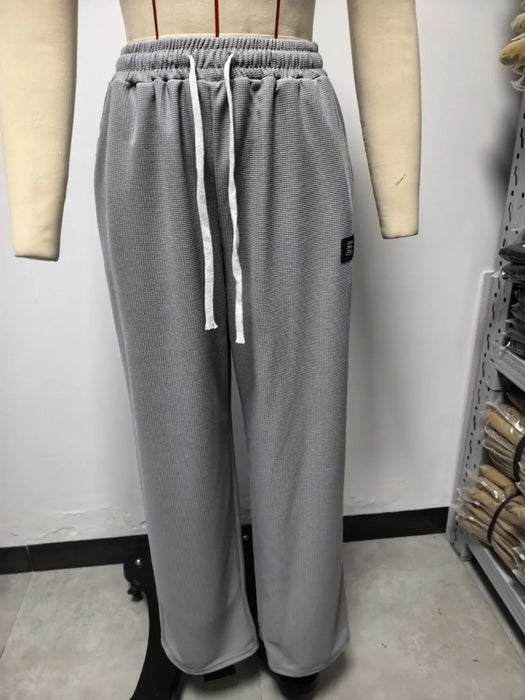 Gray sweatpants on a mannequin against a white wall.