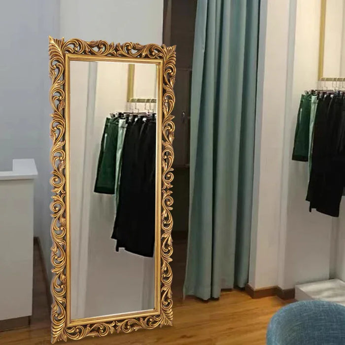 Decorative gold-framed mirror in a room with clothes and curtains.